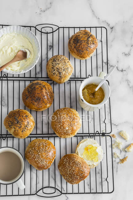 Homemade mini buns on cooling rack with cream and jam — Stock Photo