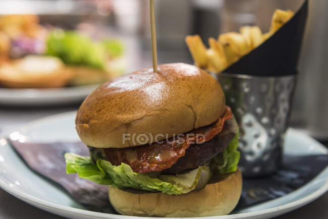 Una hamburguesa de tocino con patatas fritas - foto de stock
