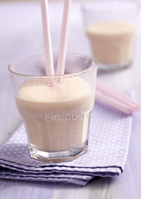 Папайя ласси в стаканах с корицей, йогуртом и соломинками — стоковое фото