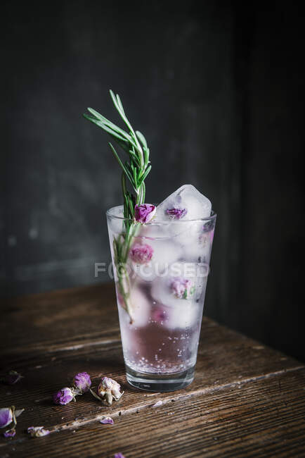 Bebida de alcohol rosa con rosas heladas, cubitos de hielo y romero - foto de stock