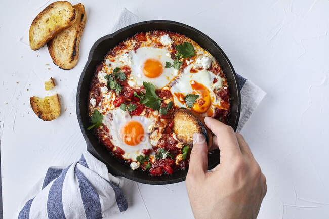 Shakshuka with tomatoes, peppers, onions and eggs prepared in cast iron skillet — Stock Photo