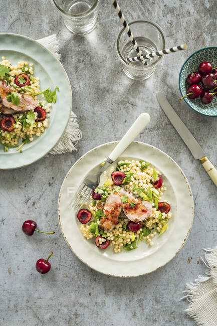 Couscous salad with fresh sweet cherries and fried duck breast - foto de stock