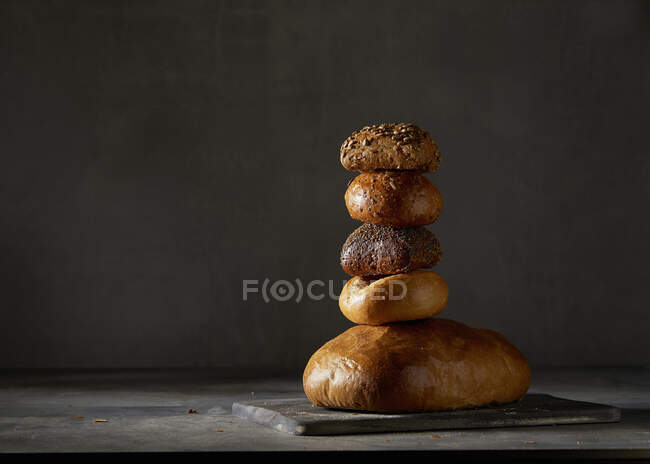 Ein Brot und vier verschiedene Brötchen, gestapelt — Stockfoto