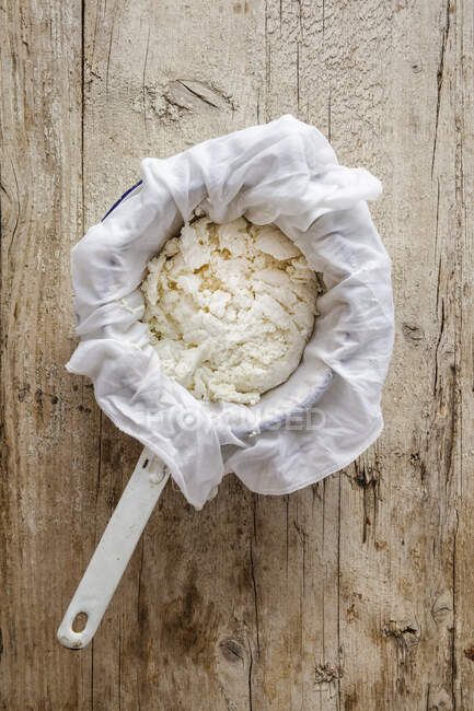 Goats cheese draining through cloth in colander — Stock Photo