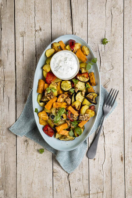 Baked vegetables with herb yogurt and caramelized walnuts — Stock Photo
