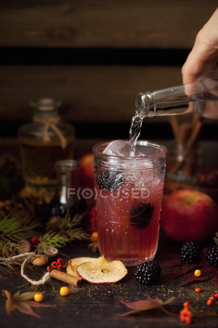 Pouring tonic water into an apple and blackberry gin and tonic — Stock Photo