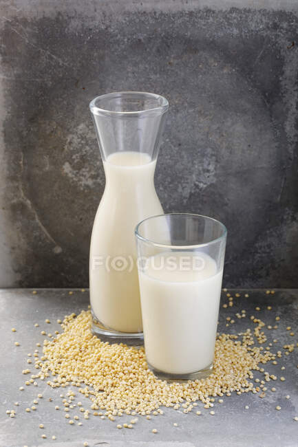 Кувшин и стакан семян молока на каменном фоне — стоковое фото