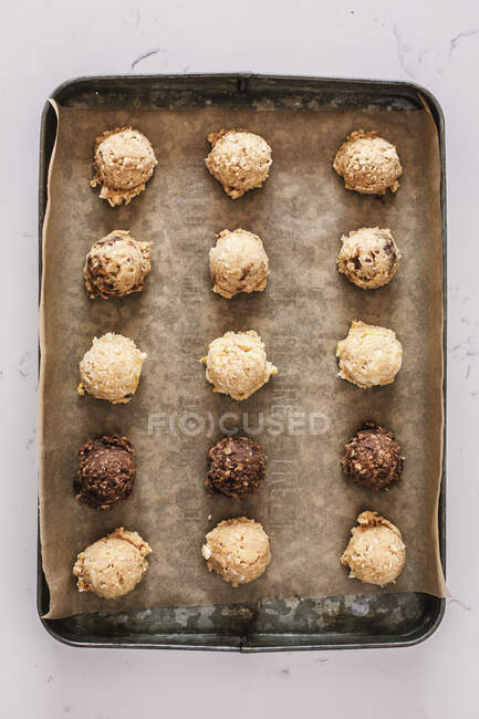 Cookie dough balls on baking paper in tin — Stock Photo