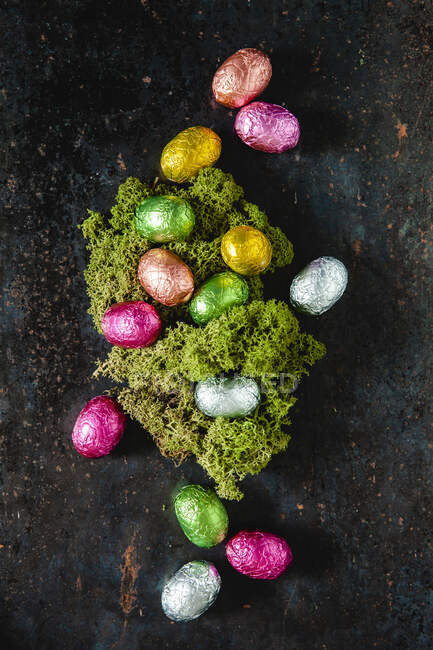 Шоколадні яйця, загорнуті в яскраву фольгу, що оточує великоднє гніздо — стокове фото