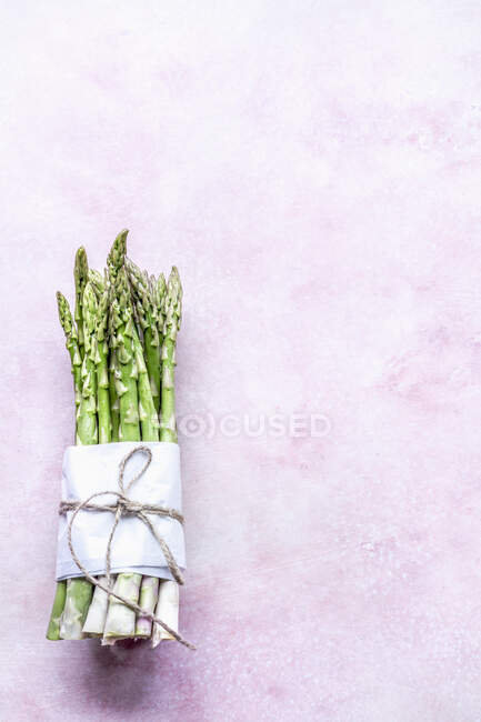 Mazzo di asparagi verdi su sfondo rosa — Foto stock