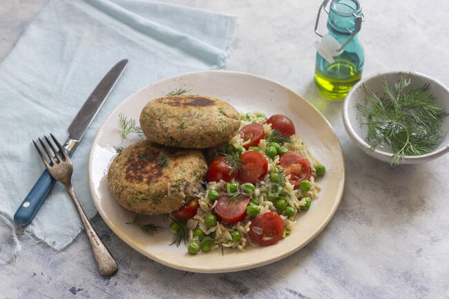 Salmon fritters with pea and cherry tomato risotto, fresh dill, olive oil — Photo de stock