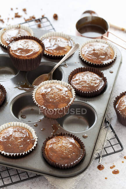 Cupcakes au caramel collant dans une boîte à pâtisserie avec sauce au caramel collant — Photo de stock