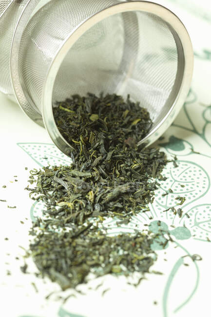 Foglie di tè verde e una tazza di bianco e nero — Foto stock