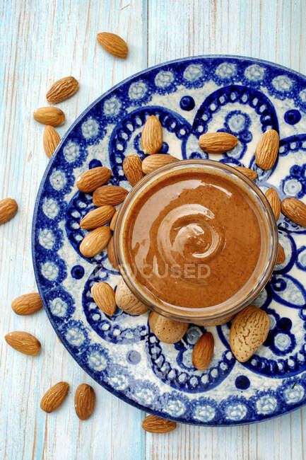 Almond cream in a small bowl on a blue ceramic plate — Stock Photo