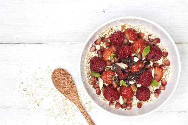 Porridge with fresh strawberries and strawberries, nuts, chocolate, mint and pomegranate seeds — Stock Photo