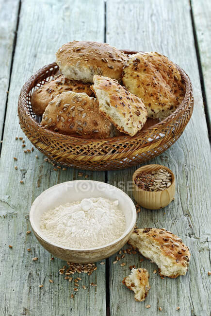 Rouleaux dans un panier à pain avec farine et graines — Photo de stock