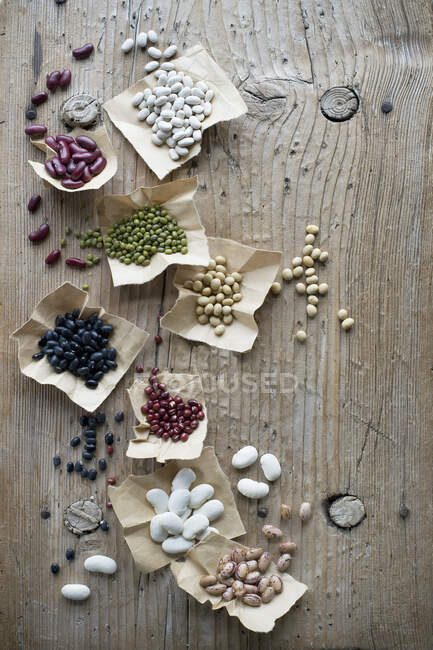 Different types of beans on a rustic wooden table — Stock Photo