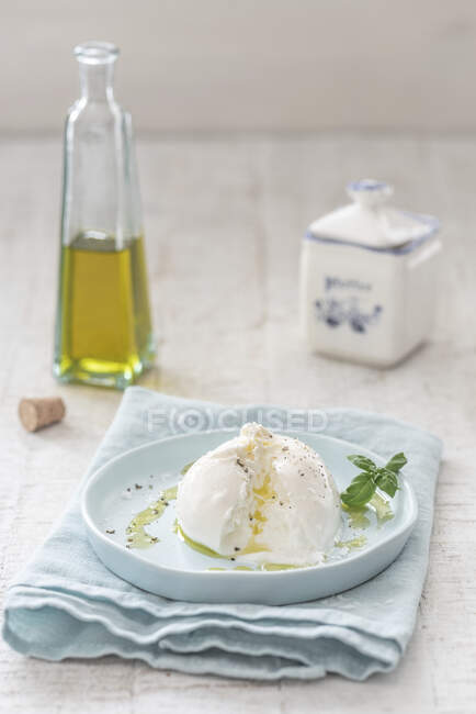 Буррата с оливковым маслом, перцем, солью и базиликом — стоковое фото
