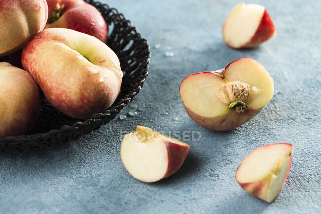 Peaches in basket and on rustic stone surface — Stock Photo