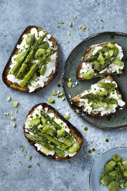 Toasts with feta, broad beans and asparagus — Stock Photo