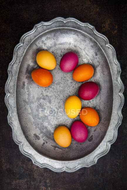 Easter eggs colored with organic dyes on pewter plate — Stock Photo