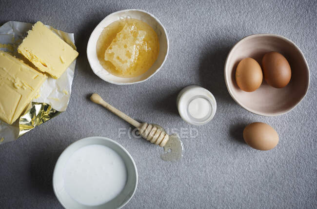 Butter, honey, eggs and milk on table surface — Stock Photo