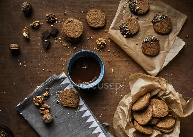 Горіхове печиво занурене в розтоплений шоколад і посипане подрібненими волоськими горіхами — стокове фото