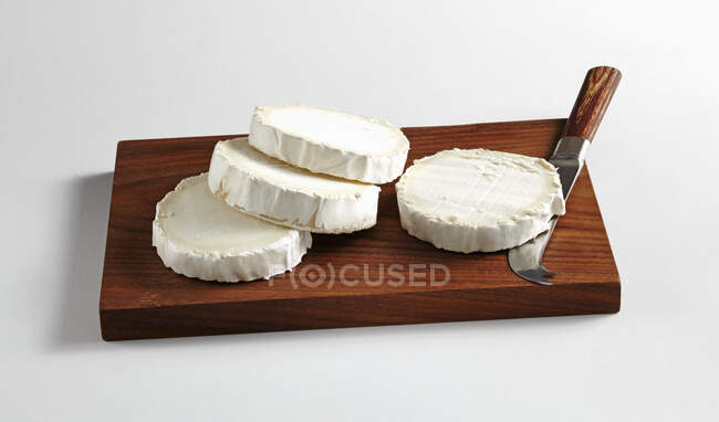 Нарізаний круглий козячий сир з сирним ножем на кухні — стокове фото