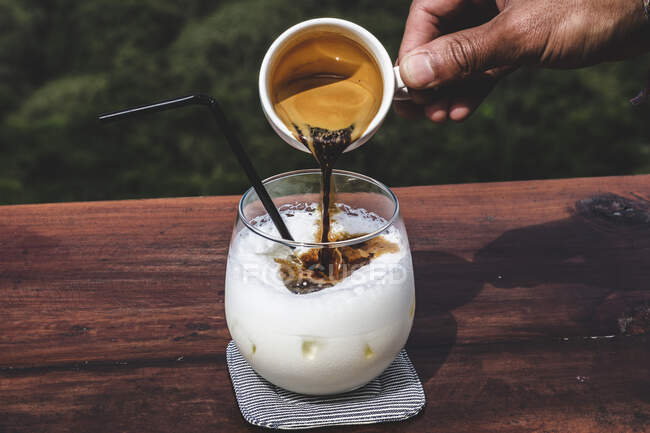 Verter el espresso en un café helado con leche - foto de stock