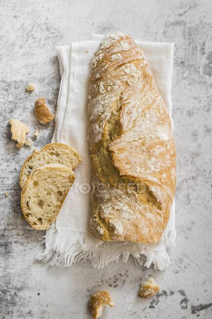 Тосканский белый хлеб с ломтиками на ткани и каменной поверхности — стоковое фото