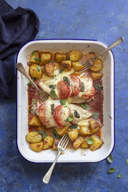 Pollo caprese: petto di pollo cotto in salsa di pomodoro con pomodoro, mozzarella, basilico e patate al forno — Foto stock