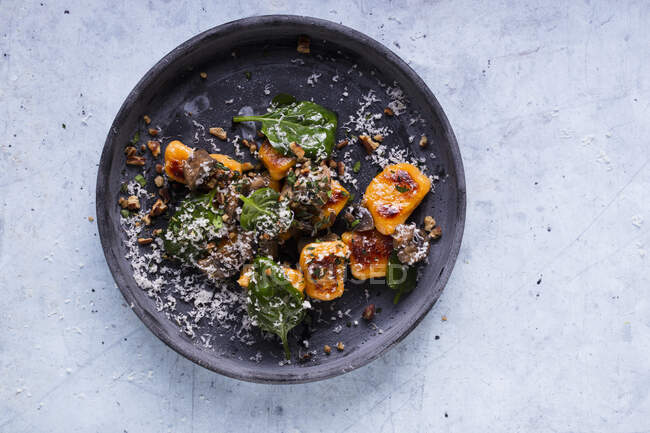 Pumpkin gnocchi with spinach and parmesan served on plate — Stock Photo