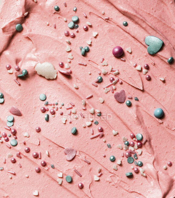 Crema de mantequilla rosa con perlas de colores y corazones - foto de stock