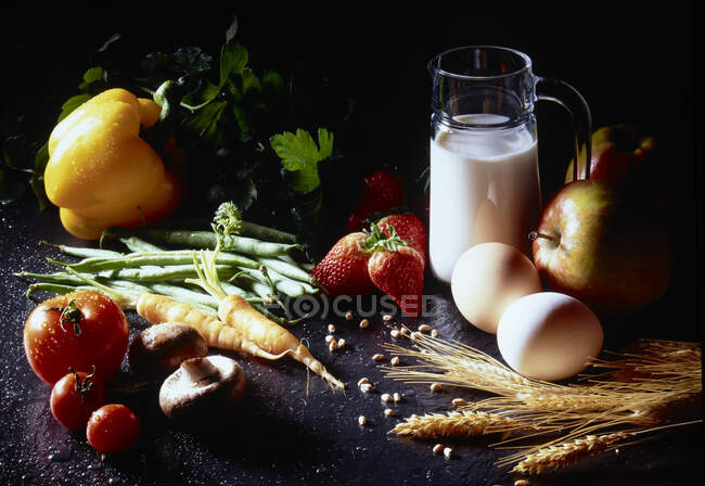 Bodegón con leche, huevos, frutas, verduras, champiñones y espigas de maíz - foto de stock