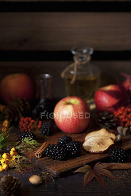 Äpfel und Brombeeren auf Holzbrettern mit Herbstlaub — Stockfoto