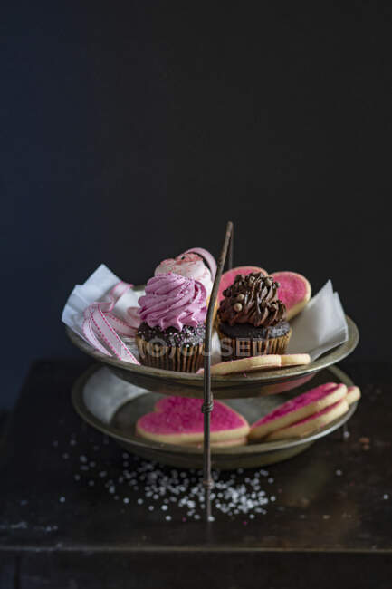 Herzförmige Kekse und Mini-Cupcakes auf einem Kuchenstand — Stockfoto