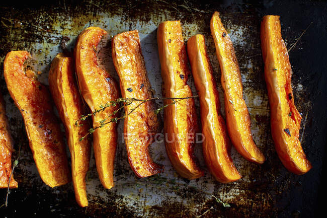 Oven-roasted pumpkin wedges on a baking tray — Stock Photo