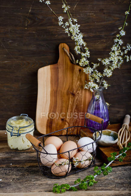 Fresh eggs in metal basket. butter in jar and herbs vine — Stock Photo