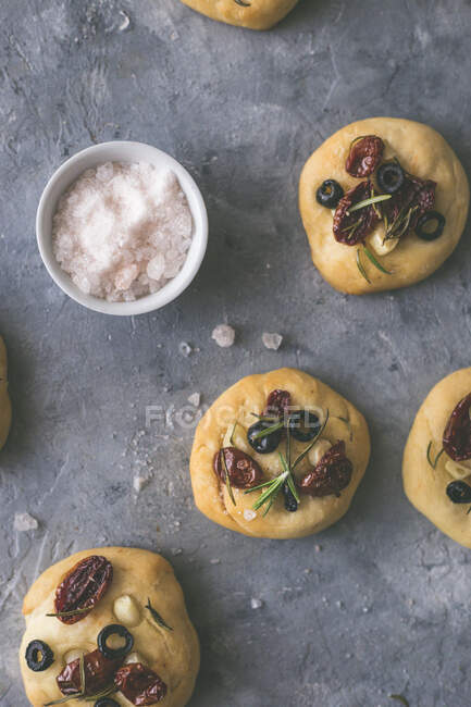 Fresh mini focaccias with tomatoes, olives and garlic — Stock Photo