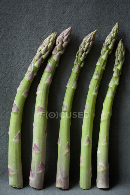 Fresh green asparagus stems by dark wall — Stock Photo