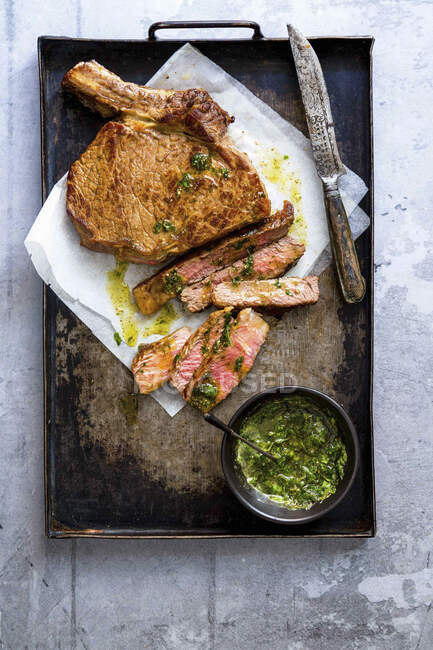 Steak de boeuf avec sauce aux herbes sur une plaque à pâtisserie — Photo de stock