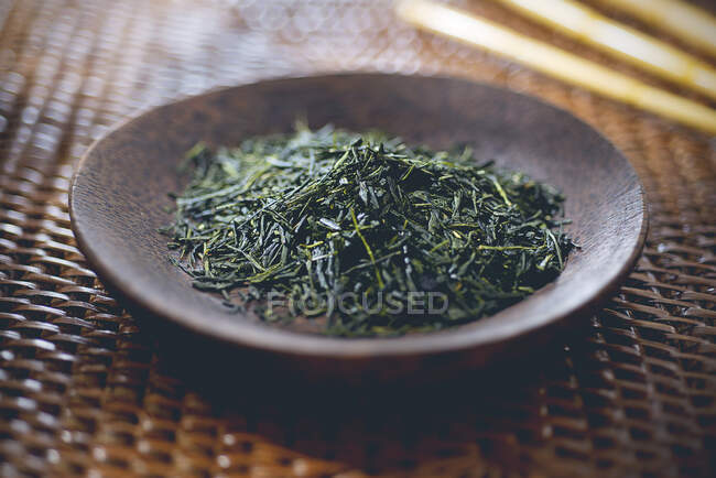 Зеленый чай: чайные листья в деревянной чаше — стоковое фото