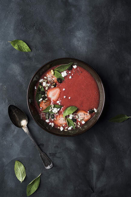 Strawberry and rhubarb cream soup, spiced with ginger and cardamom, topped with fresh mint leaves, strawberries, feta cheese, pumpkin seeds, chia seeds and sunflower seeds — Stock Photo