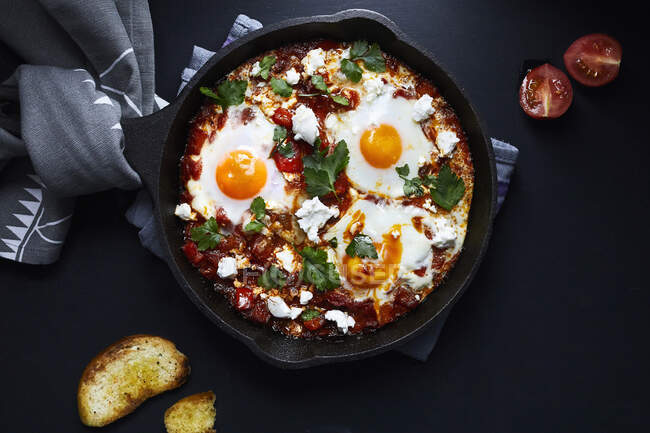 Шакшука с помидорами, перцем, луком и яйцами, приготовленными в чугунной сковороде — стоковое фото