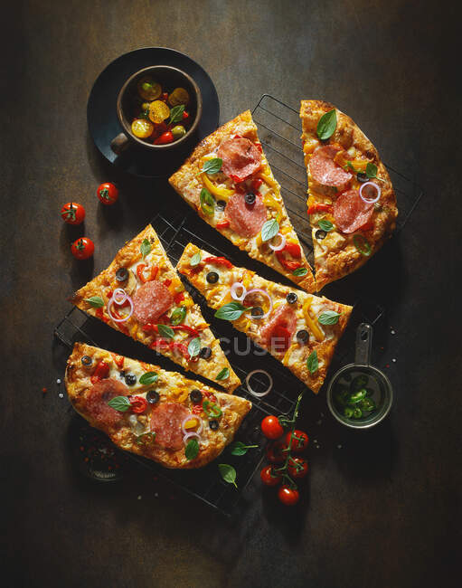 Une pizza garnie de salami, tomates et olives — Photo de stock