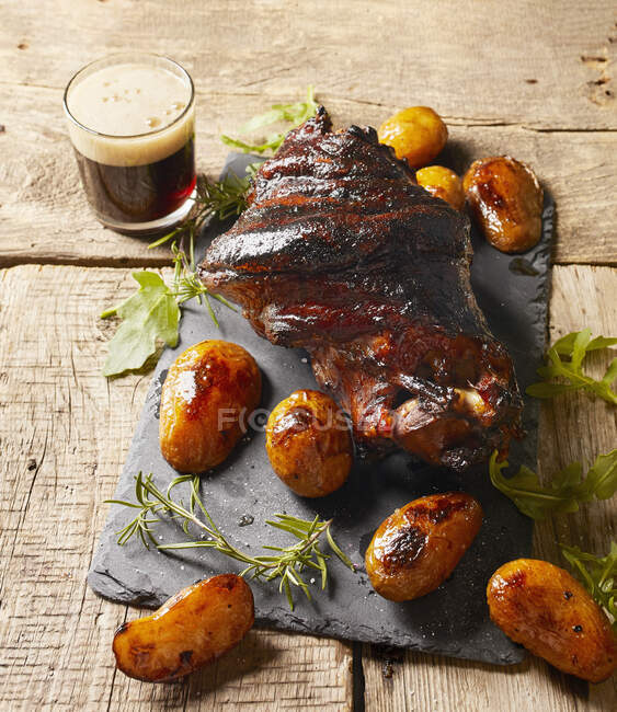 Crispy pork knuckle with baked potato and black beer — Stock Photo