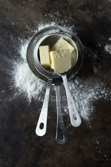 Manteiga em copos de medição de metal empilhados — Fotografia de Stock