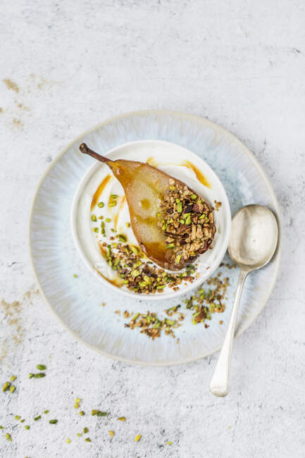 Pistachios, granola and baked vanilla pear half in bowl — Stock Photo