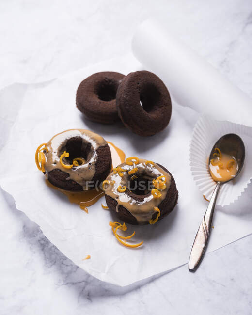 Vegan oven-baked chocolate donuts with orange icing and orange zest — Stock Photo