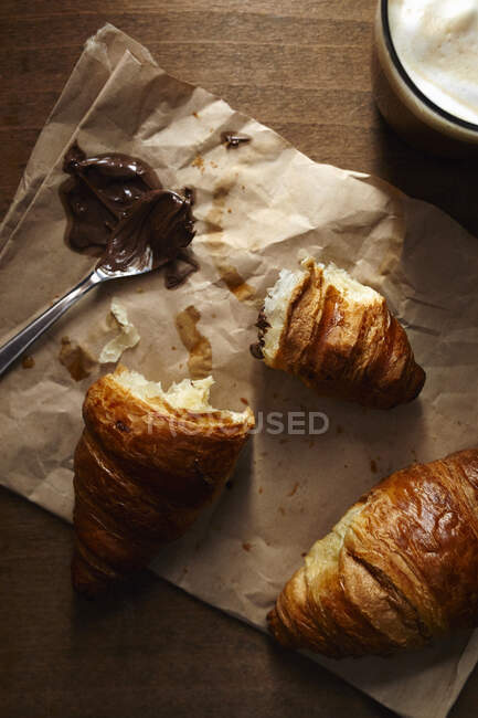 Croissant fresco con crema de avellana y café para el desayuno - foto de stock